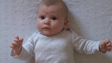 Beyaz anne babalar yeni doğan kızlarını beyaz bir battaniyenin üzerinde uzanmış kameraya bakarken çekiyorlar.