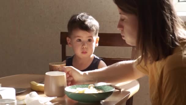 La madre caucasica spericolata si sta prendendo cura di suo figlio preparando biscotti con burro durante la colazione. — Video Stock