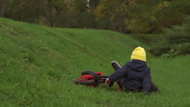 Indietro guarda il video di un ragazzo caucasico che cade mentre va in bicicletta in un campo verde e si alza per continuare — Video Stock