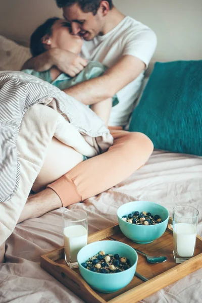 Couple caucasien au lit embrassant et embrassant avant de manger des céréales et du lait ensemble — Photo