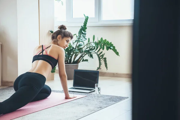 Volver ver foto de una mujer caucásica en ropa deportiva teniendo lección de fitness con un ordenador portátil en el suelo — Foto de Stock