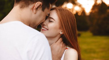 Kafkasyalı bir kadının arka plan fotoğrafı, çilli, kızıl saçlı kocası parkı öpüyor ve kucaklıyor.