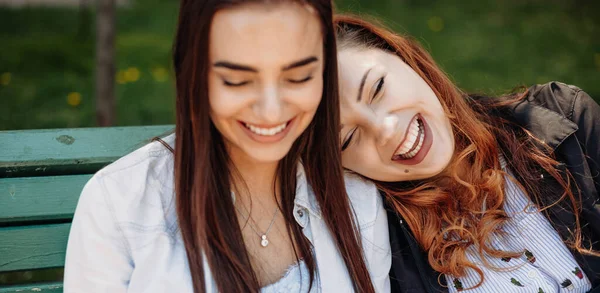 Mujer de pelo rojo regordeta acostada sobre su amigo en el parque en el banco y sonreír — Foto de Stock