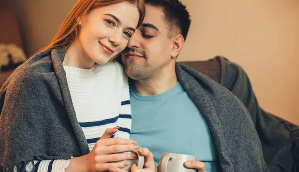 Charming ginger caucasian woman with red hair lying on the sofa with her boyfriend and having a tea together — Stock Photo, Image