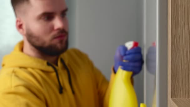 El hombre caucásico con barba está desinfectando la casa y limpiándola del polvo usando guantes. — Vídeos de Stock