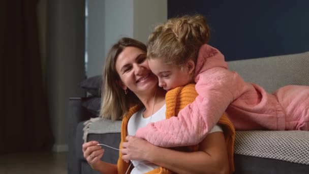 Lieve moeder en haar dochter spelen op de vloer samen luisteren naar mijmeren door middel van oortelefoons — Stockvideo