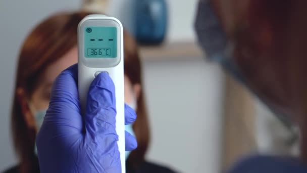 El médico caucásico está midiendo la temperatura corporal de un paciente usando un termómetro eléctrico — Vídeos de Stock