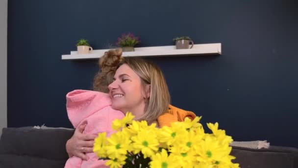 Kleine dochter is het geven van haar moeder een emmer van gele bloemen omarmen samen en glimlach — Stockvideo