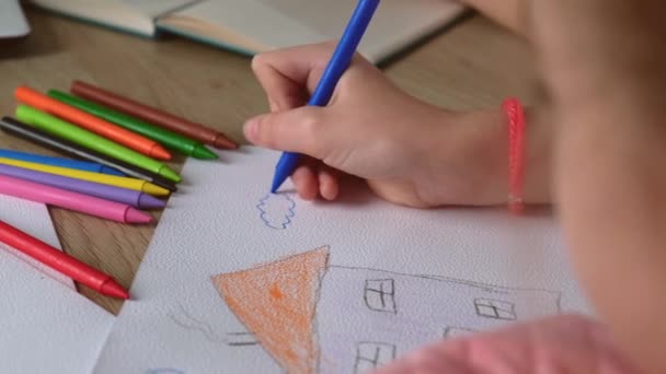 Menina pequena está desenhando em papel com lápis de cor, enquanto sua mãe está trabalhando nas proximidades — Vídeo de Stock