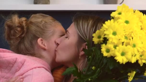 Mère et fille caucasiennes embrassent avec un bouquet de fleurs souriantes et s'embrassent — Video