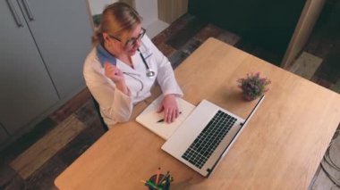 Üst düzey bir doktorun, dizüstü bilgisayar kullanan bir hastayla çevrimiçi istişarede bulunduğu bir video.