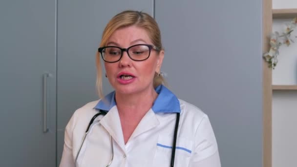 Kaukasische arts heeft een online ontmoeting met de patiënten die met hen praten met behulp van een laptop — Stockvideo
