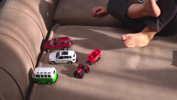 Barfodet dreng leger med plastbiler på sofaen, mens hendes mor giver ham en hi fem – Stock-video