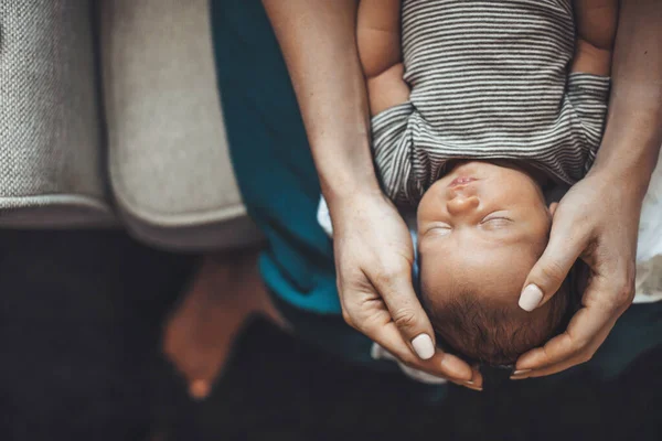 Upper view photo of a caucasian mother holding her newborn daughter on the knees while she is sleeping