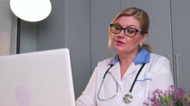 Kıdemli doktor internetten bilgisayarla müşteriyle konuşuyor ve uzaktan konsültasyon yapıyor.