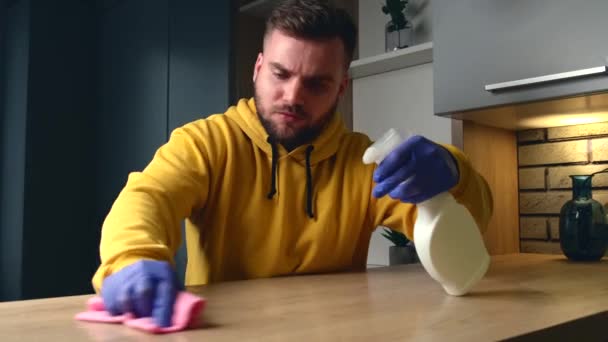 Hombre caucásico con guantes y suéter amarillo está limpiando y desinfectando la casa con spray — Vídeos de Stock