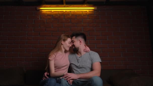 Kaukaskie para całowanie i przytulanie podczas mając a randka siedzi na kanapie z mało światła w romantyczny atmosfera — Wideo stockowe