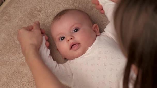 Mãe caucasiana está brincando com sua filha na cama movendo as mãos — Vídeo de Stock