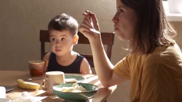 Caucasian adorable family eating breakfast together at the table while looking at something in the room — Stock Video