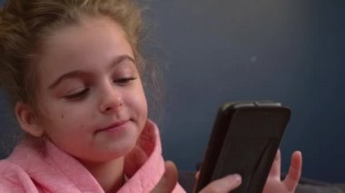 Kafkasyalı bir kızın kanepede oturup internette gezinirken cep telefonu kullandığı videoyu kapat.