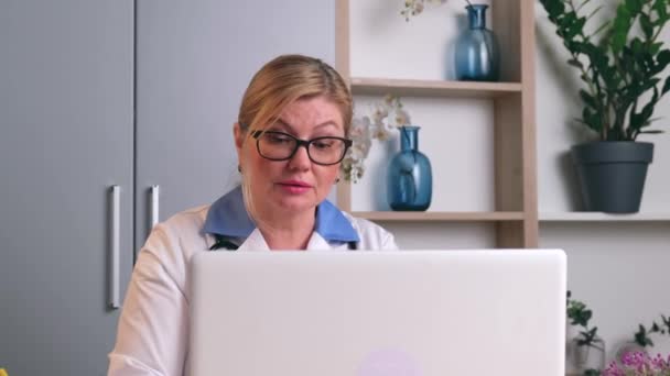 Běloška mluví online s pacientkou na notebooku, která vysvětluje postupy léčby na dálku. — Stock video