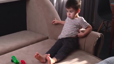 Kafkas çocuk kanepede uzanıyor ve tek başına oynayan oyuncaklarını izliyor.