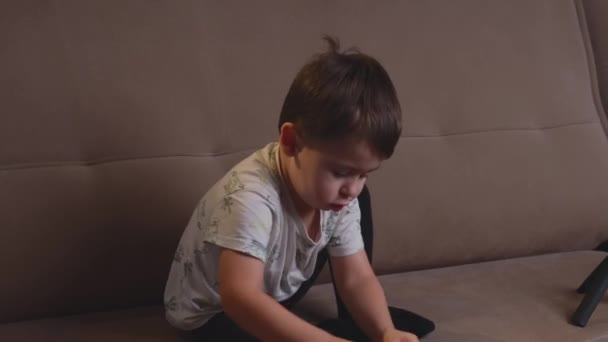 Kavkazský chlapec simuluje řízení auta na gauči hraje s autíčky — Stock video