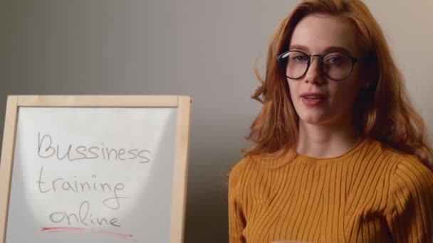 Caucásico jengibre dama está enseñando lecciones de negocios en línea hablando en la cámara cerca del tablero — Vídeos de Stock