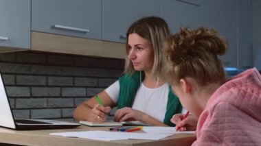 Beyaz kadın, kızı yakınlarda çizim yaparken evden bilgisayarda çalışıyor.