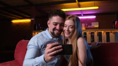 Kafkasyalı çilli kadın ve sevgilisi çıkarken telefonla selfie çekiyorlar.