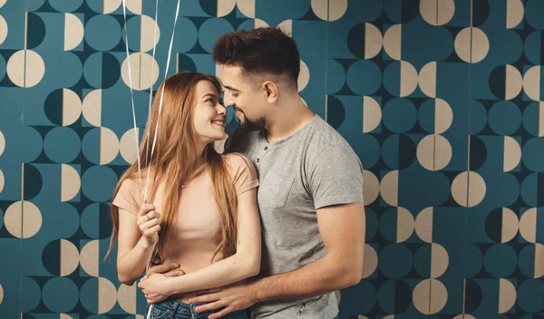 Kaukasiska par ler ansikte mot ansikte medan du håller några ballonger på en blå vägg på studio — Stockfoto