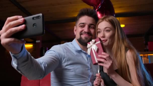 Coppia fare un selfie utilizzando un telefono e sorridere mentre tenere un regalo e palloncini d'aria — Video Stock