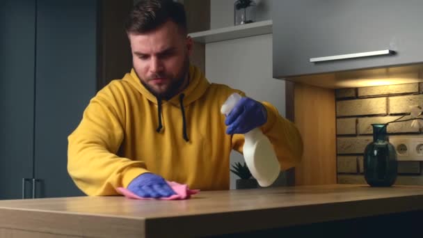 Blanke man is het schoonmaken van een tafel met antiseptische spray en veeg met handschoenen — Stockvideo