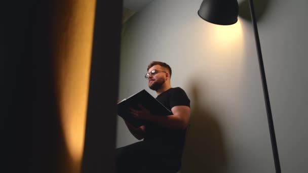 Brodaty mężczyzna kaukaski jest prowadzenie szkolenia biznesowego online mówienie przed kamerą z copybook podczas siedzenia na ścianie studio — Wideo stockowe