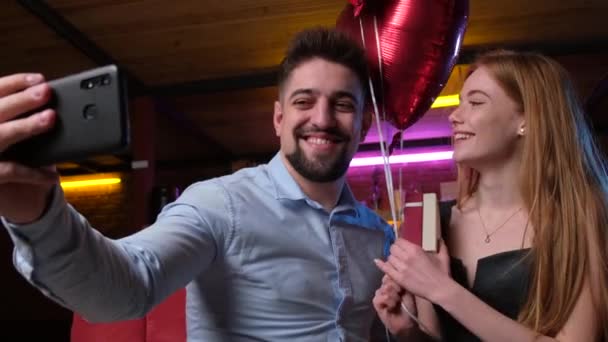 Encantador casal fazendo uma selfie enquanto ele lhe deu um presente e balões de ar — Vídeo de Stock