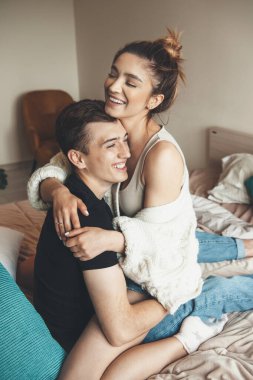 Sevimli bir adam sabahları yatakta oynarken sevgilisini kucaklıyor.