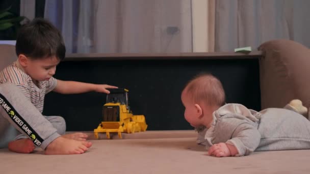 Petit garçon caucasien joue sur le canapé avec une voiture jouet en plastique tandis que le frère nouveau-né est couché sur le canapé — Video