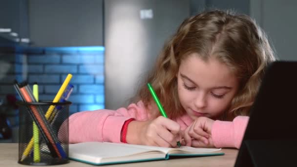 Chica concentrada está escribiendo el tema durante la videollamada en línea sonriendo en la tableta — Vídeo de stock