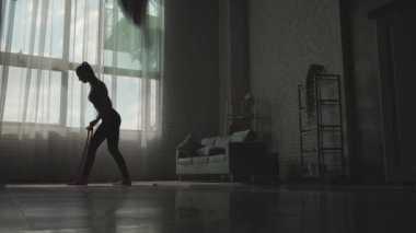 Beyaz kadın, pencerenin yanında elastik bantlarla antrenman yapıyor.