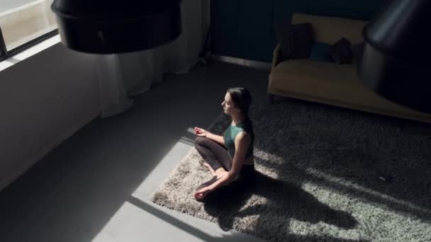 Kaukasische Frau meditiert zu Hause vor einem Fenster auf dem Boden — Stockvideo