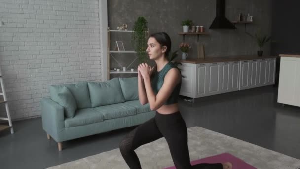 Mulher branca em casa está praticando fitness agachamento em um tapete especial — Vídeo de Stock