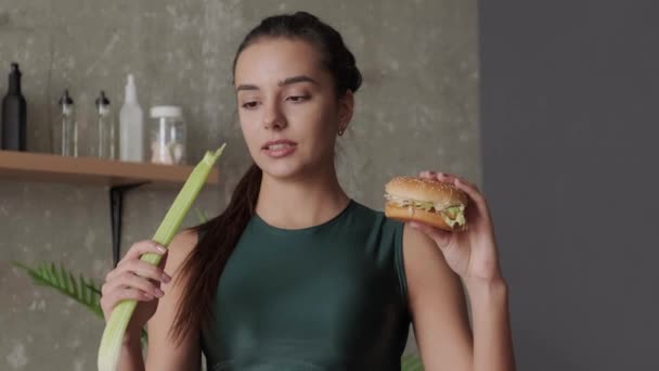 Beyaz kadın sağlıklı vejetaryen yemeği ve hamburger arasında seçim yapıyor. — Stok video