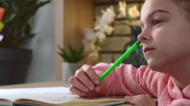 Kafkasyalı bir kızın ödevini yaptığı videoyu kapayarak konuyu deftere yazarak ve gülümseyerek.