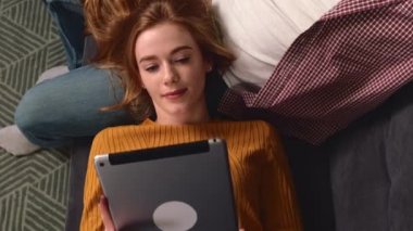 Çilleri aşığının dizlerinde tablet kullanan kızıl bir kadının en iyi fotoğrafı.