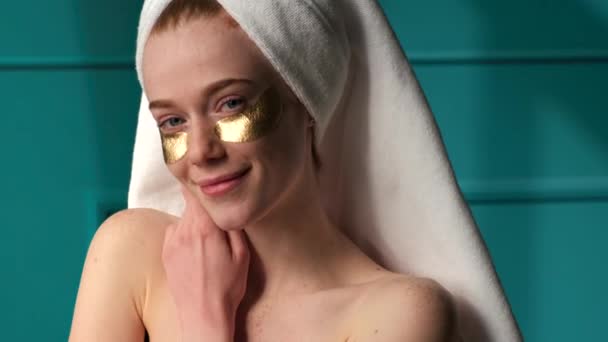 Імбирна жінка з веснянками в золотих плямах очей посміхається на камеру з голими плечима — стокове відео