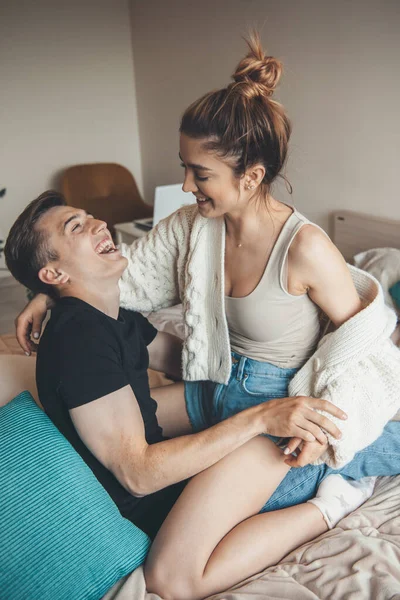 Caucasiano casal amoroso estão jogando na cama abraçando e sorrindo um para o outro — Fotografia de Stock