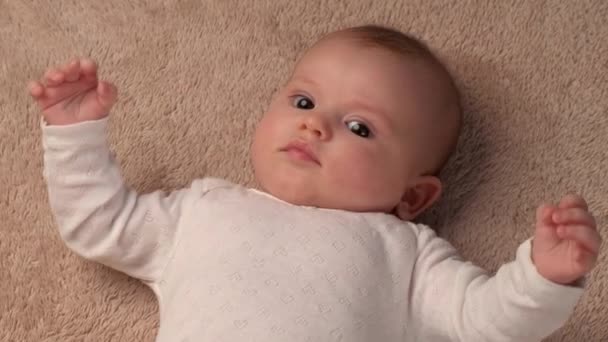Vídeo de vista superior de un bebé recién nacido acostado en la cama y moviéndose mientras alguien está jugando con ella — Vídeos de Stock