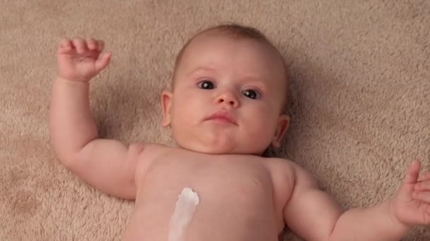 新生児の体のマッサージに特別なクリームを適用している白人の親の上ビュービデオ — ストック動画