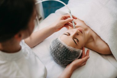 Cilt bakımı sırasında beyaz bir kaplıca çalışanının müşterileri teçhizatla temizlerken çekilmiş üst görüntü fotoğrafı.