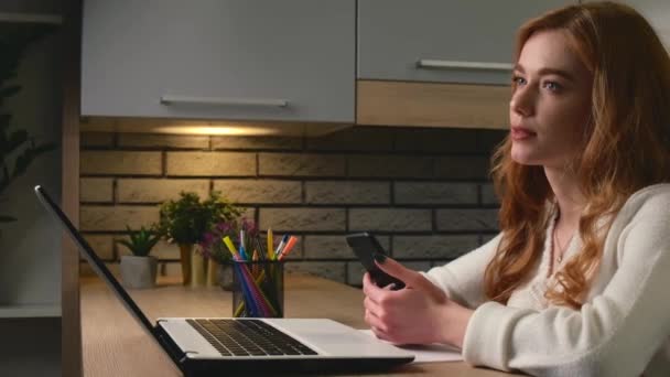 Oldalnézet videó egy vörös nő szeplős beszél valakivel a konyhában használata közben egy laptop — Stock videók